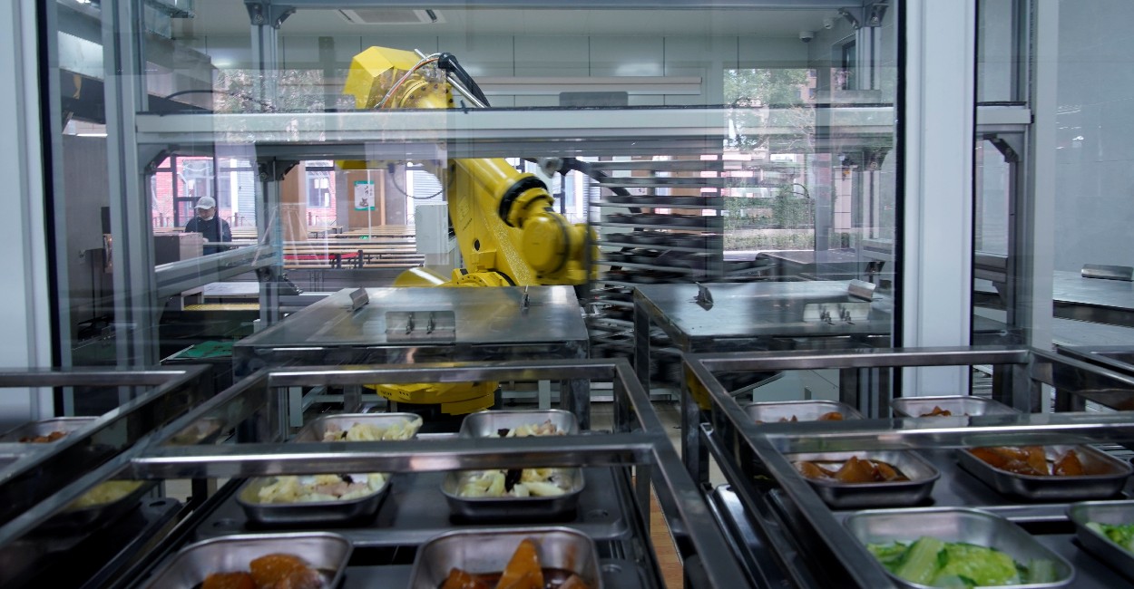 El robot coloca los platos en bandejas que van a una cinta transportadora. | Foto: REUTERS.