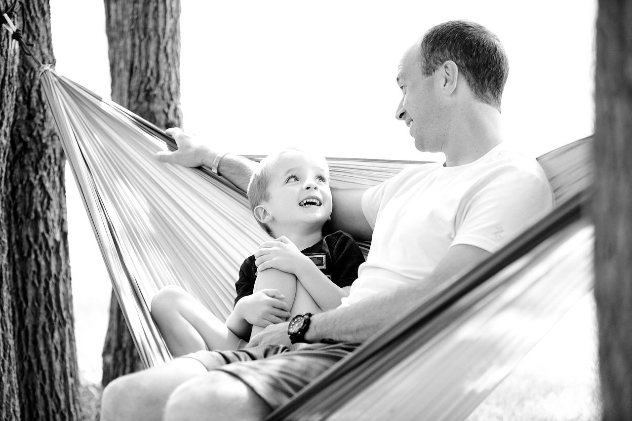 Papá con su hijo, sentados en una amaca.